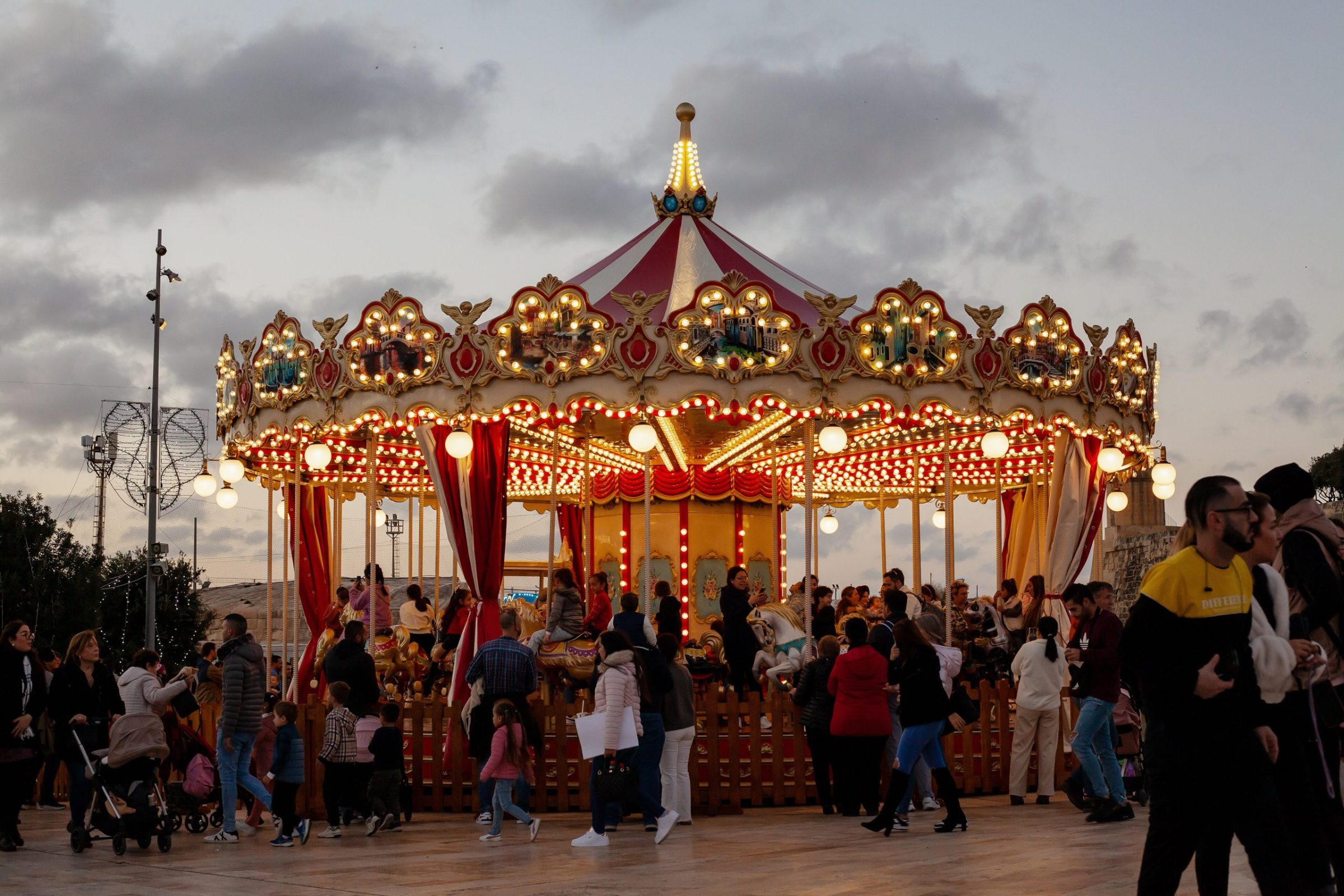 Families around a lit Christmas carousel in Valletta at dusk